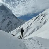 Persona en un sendero nevado, rodeada de imponentes montañas cubiertas de nieve. El senderismo nieve es una aventura inolvidable.