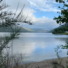 Un lago sereno en el West Highland Way, con colinas cubiertas de vegetación y un cielo nublado.