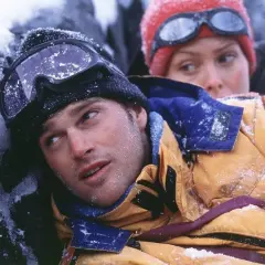 Dos escaladores, cubiertos de nieve, luchan contra el frío en una escena de una película de montaña.