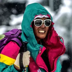 Pasang Lhamu Sherpa, con gafas de sol y gorro, se enfrenta a la nieve con una colorida chaqueta y mochila.