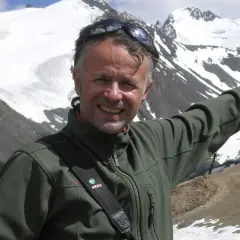 Juanjo Garra, alpinista sonriente, posa con montañas nevadas de fondo.