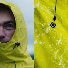 Primer plano de un hombre con capucha amarilla y detalle de tela amarilla con gotas de agua, demostrando la columna de agua impermeabilidad.