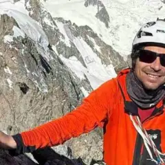 Vivian Bruchez, sonriente y con casco, escala una montaña rocosa y nevada.