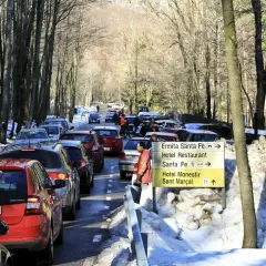 Tráfico en el Montseny con nieve. Coches en fila por la carretera nevada, señalizando la ermita y el hotel.