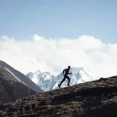 Stephane Brosse corre por una ladera rocosa con picos nevados de fondo.