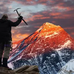 Erik Weihenmayer, escalador, levanta su piolet ante un Everest anaranjado al amanecer.