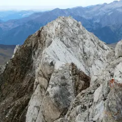 Cresta rocosa y escarpada en el **valle de Vallibierna**, con montañas azules y brumosas al fondo.