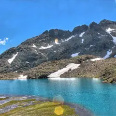 Espectaculares lagos azules en Panticosa, rodeados de montañas rocosas con nieve y un cielo azul intenso.