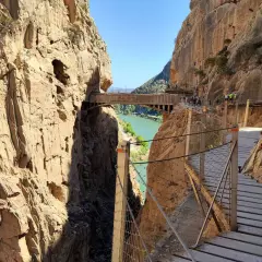 Pasarela de madera sobre un cañón con río verde. Los impresionantes montes bonitos se elevan a ambos lados, creando un paisaje espectacular.