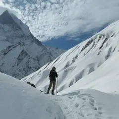 Persona en un sendero nevado, rodeada de imponentes montañas cubiertas de nieve. El senderismo nieve es una aventura inolvidable.