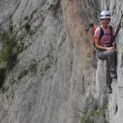 Mujer sonríe en una vía ferrata, disfrutando de la escalada en Benasque.