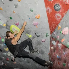 Un escalador se aferra a la pared con sus dedos, buscando el próximo agarre.