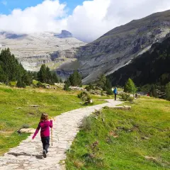 Niños disfrutan de la ruta Cola de Caballo, un camino de piedra serpentea entre prados verdes y montañas imponentes.