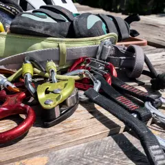 Equipo de escalada para rocódromo: arnés, pies de gato, mosquetones, descendedor y cuerda.