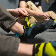 Persona se prepara para escalar, ajustando sus pies de gato. Aprende como lavar pies de gato para mantenerlos en óptimas condiciones.