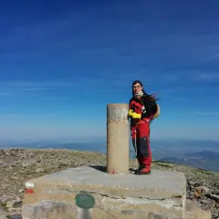 Cumbre del Moncayo, disfrutando de la ruta circular. Una excursionista posa junto al vértice geodésico con bastones de trekking.