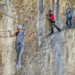 Tres personas disfrutan de una emocionante escalada con cuerda en una pared rocosa.