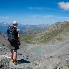 Senderismo en las majestuosas cordilleras del mundo, contemplando un lago turquesa y senderos serpenteantes.