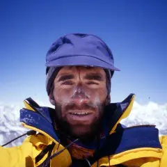 Erhard Loretan, con el rostro marcado por el sol y la nieve, sonríe desde la cima de una montaña.