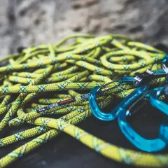 Cuerda de escalada amarilla y verde con mosquetones azules. Lista para lavar y usar en la próxima aventura.