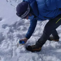 Persona en la arva montaña, con equipo de rescate, buscando algo en la nieve.