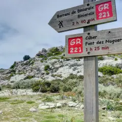 Señalización de ruta GR 221 en un sistema montañoso rocoso. Indica senderos a Barranc de Biniaraix y Cúber.