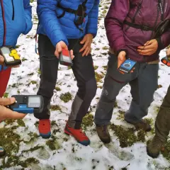 Personas en la nieve sostienen varios dispositivos de búsqueda de avalanchas, como el PIEPS, para una lección de seguridad en montaña.