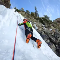 Escalador en hielo en los Pirineos, disfrutando de corredores fáciles con crampones y piolet.