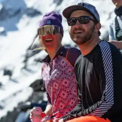 Dos amigos disfrutan del sol en la montaña, abrigados con ropa de poliamida.