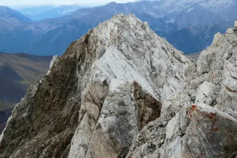 Cresta rocosa y escarpada en el **valle de Vallibierna**, con montañas azules y brumosas al fondo.