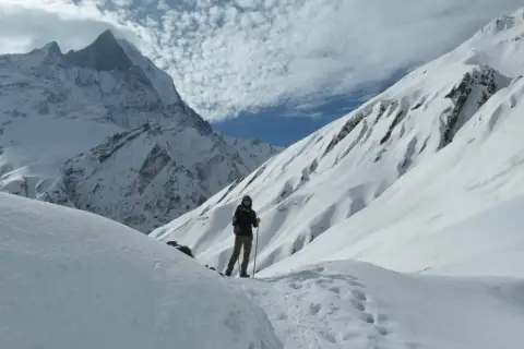 Persona en un sendero nevado, rodeada de imponentes montañas cubiertas de nieve. El senderismo nieve es una aventura inolvidable.