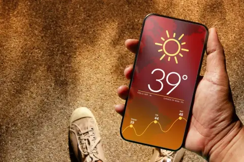 Mano sostiene móvil con app del tiempo mostrando 39°, ¿cuál es la mejor app del tiempo? El pronóstico indica calor extremo.