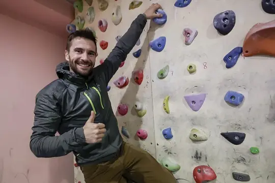 Edu Marin sonríe y da pulgar arriba mientras escala en un rocódromo.