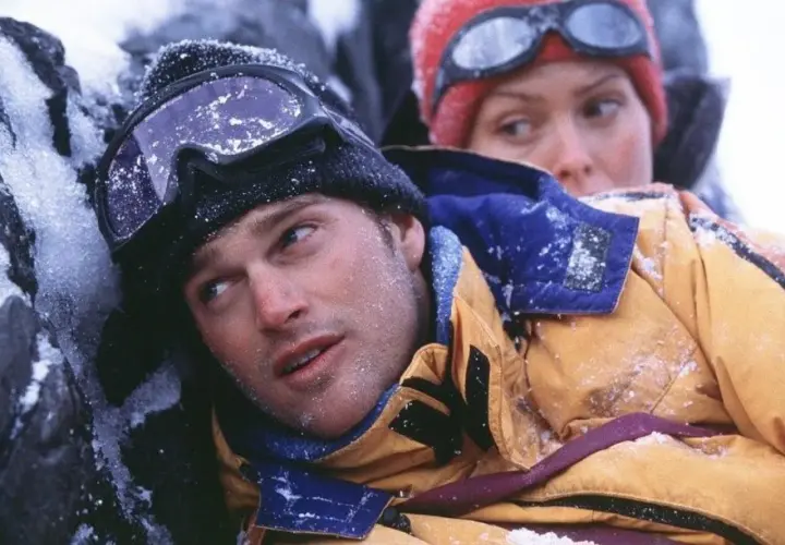 Dos escaladores, cubiertos de nieve, luchan contra el frío en una escena de una película de montaña.
