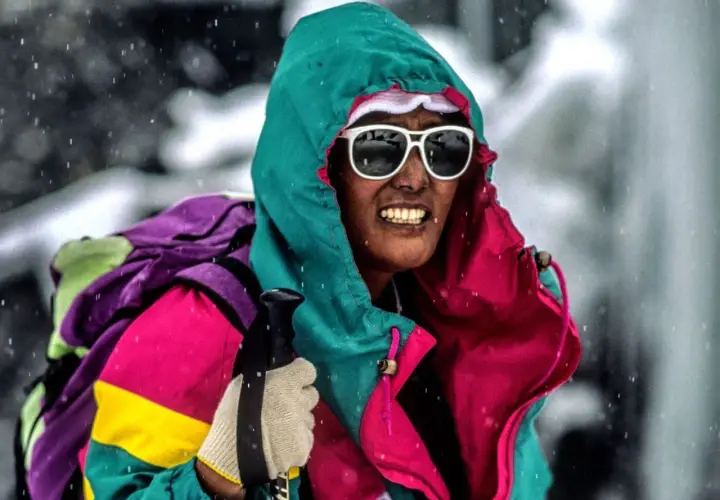 Pasang Lhamu Sherpa, con gafas de sol y gorro, se enfrenta a la nieve con una colorida chaqueta y mochila.