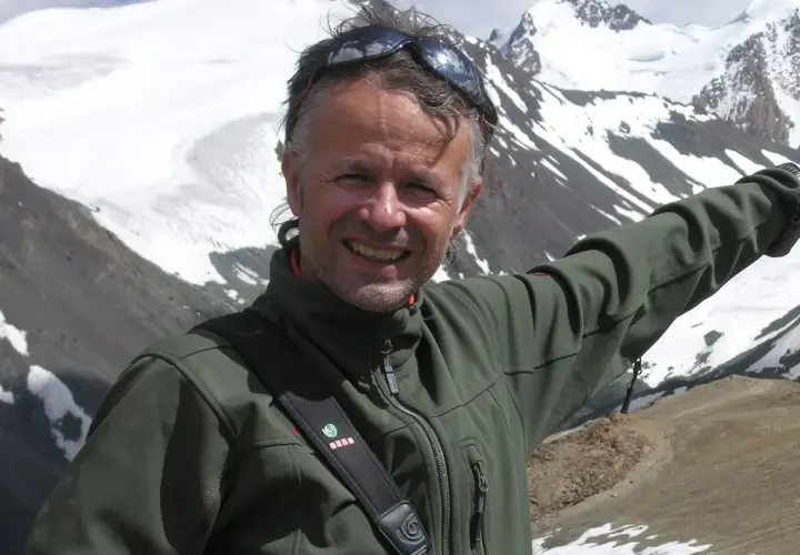 Juanjo Garra, alpinista sonriente, posa con montañas nevadas de fondo.