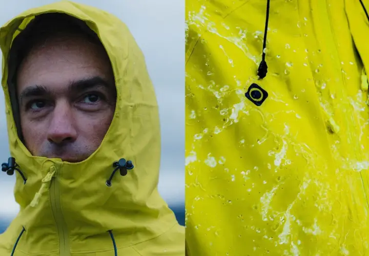Primer plano de un hombre con capucha amarilla y detalle de tela amarilla con gotas de agua, demostrando la columna de agua impermeabilidad.
