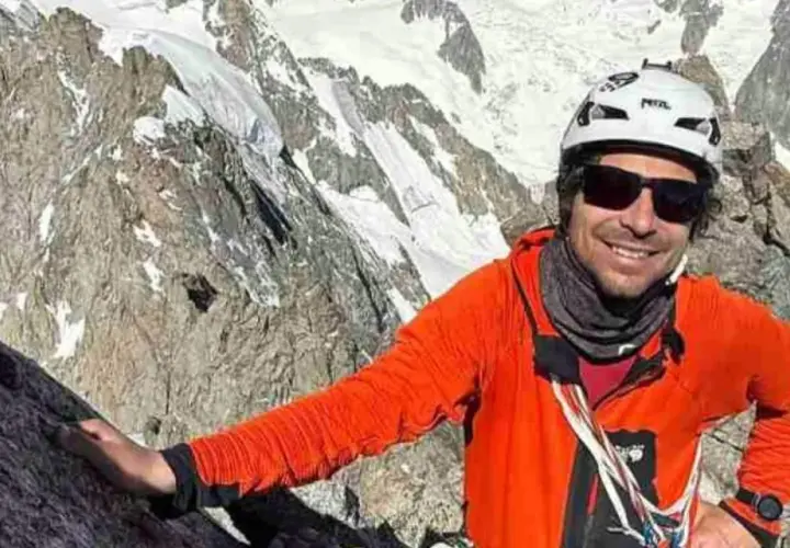 Vivian Bruchez, sonriente y con casco, escala una montaña rocosa y nevada.