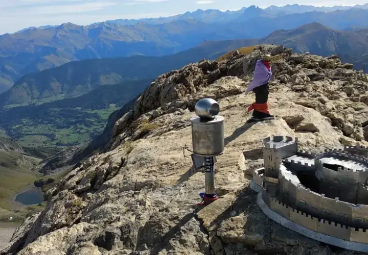 En la cima de una montaña, un monumento con forma de castillo y un poste con una esfera metálica. Al fondo, un valle verde y montañas azules. El **erregeen mahaia** es un lugar de ensueño.