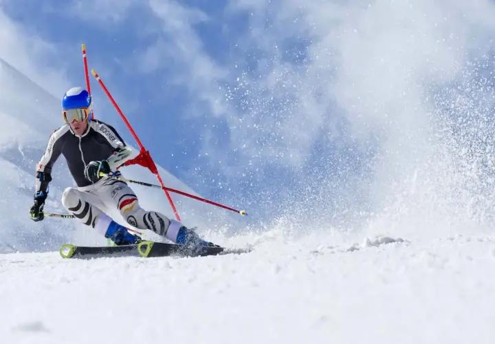 Esquiador compitiendo en slalom, mostrando la diferencia entre esquí alpino y de montaña en una pista nevada.