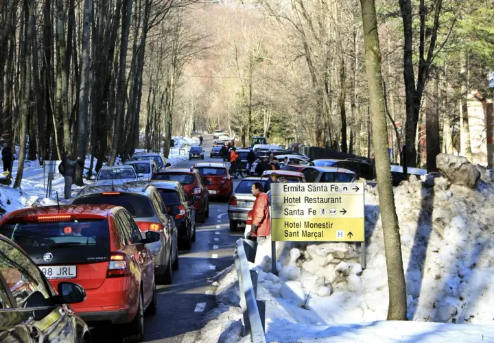 Tráfico en el Montseny con nieve. Coches en fila por la carretera nevada, señalizando la ermita y el hotel.