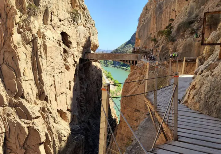 Pasarela de madera sobre un cañón con río verde. Los impresionantes montes bonitos se elevan a ambos lados, creando un paisaje espectacular.
