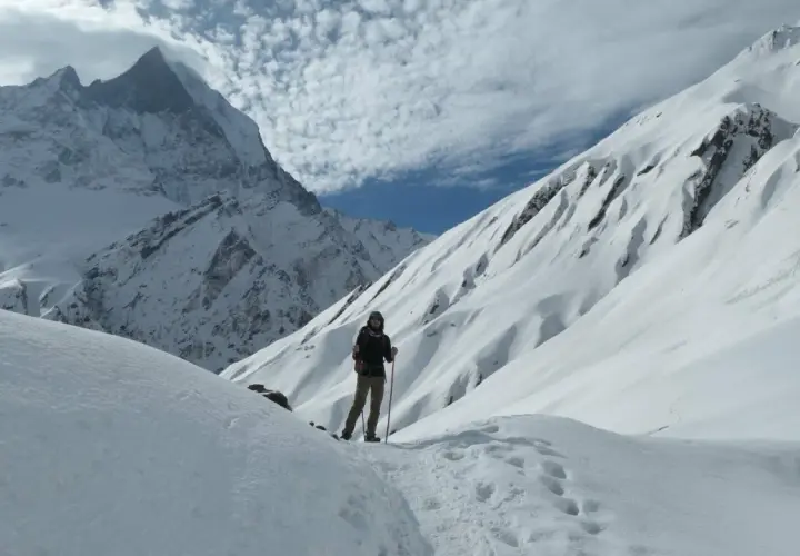 Persona en un sendero nevado, rodeada de imponentes montañas cubiertas de nieve. El senderismo nieve es una aventura inolvidable.
