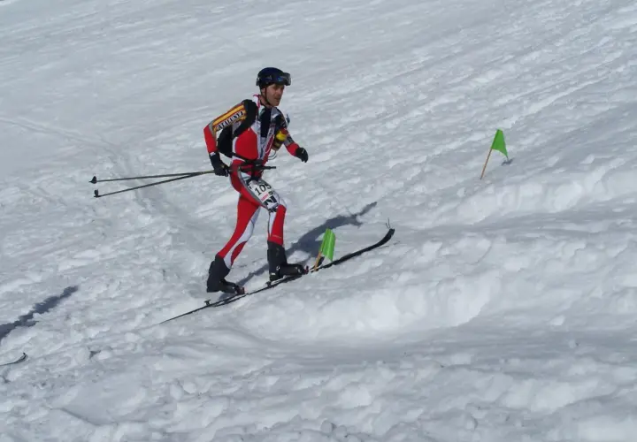 Agustí Roc, esquiador de montaña, compite en una carrera con esquís y bastones, marcado por banderas verdes en la nieve.
