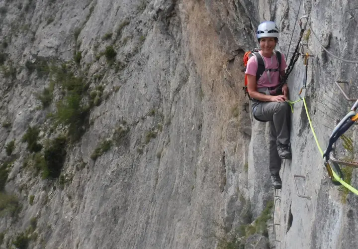 Mujer sonríe en una vía ferrata, disfrutando de la escalada en Benasque.