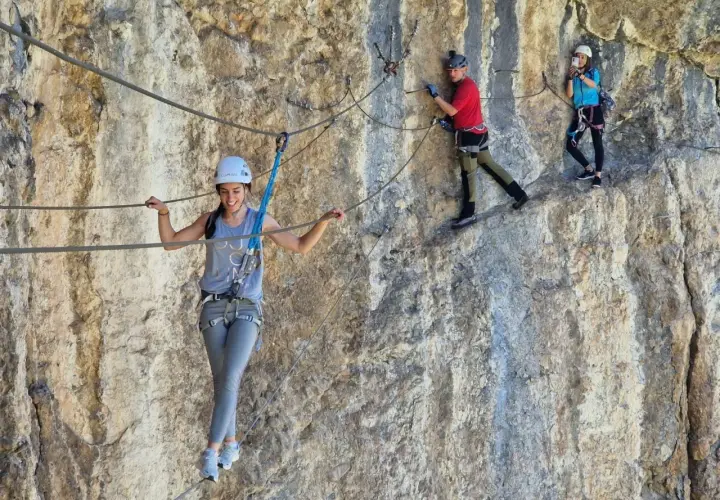 Tres personas disfrutan de una emocionante escalada con cuerda en una pared rocosa.