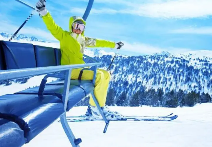 Mujer emocionada en telesilla, lista para hacer sky en la montaña nevada.