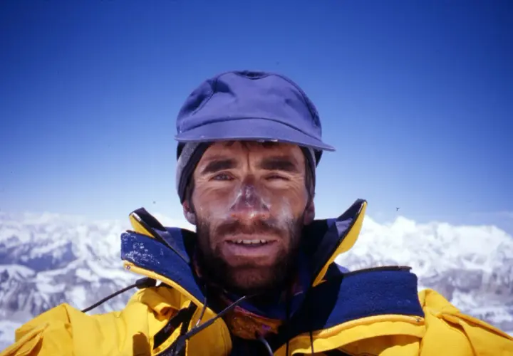 Erhard Loretan, con el rostro marcado por el sol y la nieve, sonríe desde la cima de una montaña.