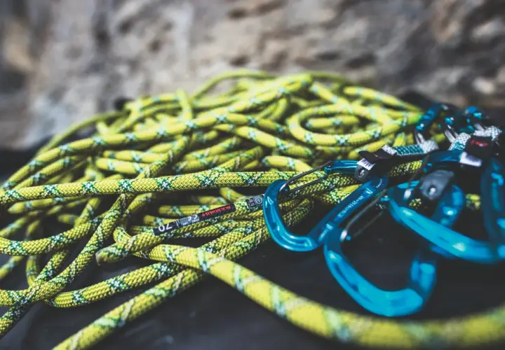 Cuerda de escalada amarilla y verde con mosquetones azules. Lista para lavar y usar en la próxima aventura.