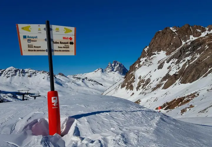 Señalización en la estación de esquí de Formigal, indicando pistas y servicios. Montañas nevadas y cielo azul.